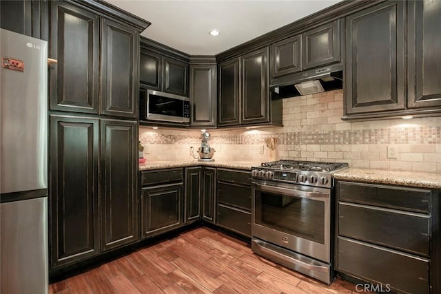 7129 Forbes Ave, Van Nuys, CA 91406 - kitchen featuring appliances with stainless steel finishes, under cabinet range hood, backsplash, wood finished floors, and light stone countertops
