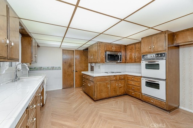 41202 Collegian Way, Hemet, CA 92544 - kitchen featuring white appliances, tile countertops, brown cabinetry, baseboards, and a paneled ceiling