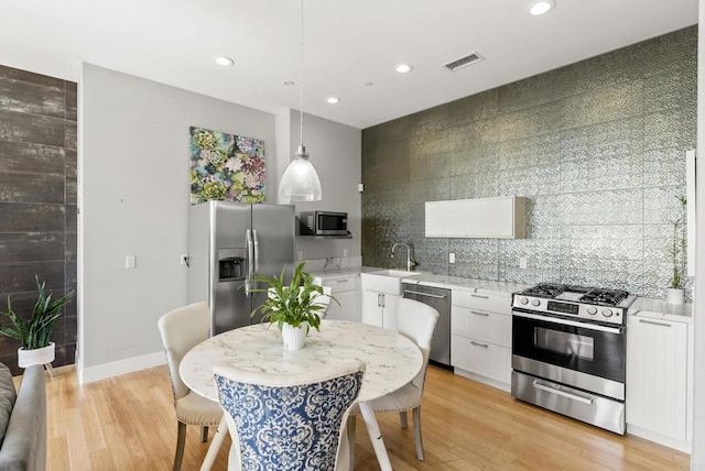 14220 Green Valley Ct, Scripps Miramar, CA 92131 - kitchen featuring appliances with stainless steel finishes, a sink, white cabinets, recessed lighting, and tasteful backsplash