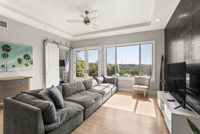 14220 Green Valley Ct, Scripps Miramar, CA 92131 - living area featuring a tray ceiling, light wood-style floors, baseboards, a barn door, and recessed lighting