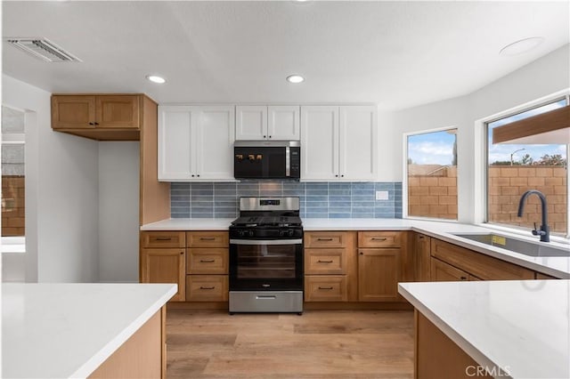 37109 Daisy St, Palmdale, CA 93550 - kitchen with appliances with stainless steel finishes, a sink, light wood finished floors, light countertops, and white cabinetry