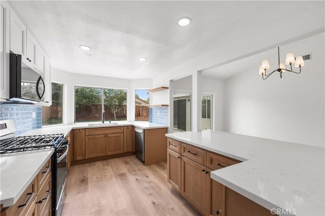 37109 Daisy St, Palmdale, CA 93550 - kitchen with appliances with stainless steel finishes, tasteful backsplash, light wood-style flooring, a chandelier, and a sink