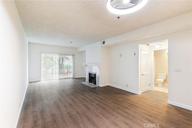 2905 Montrose Ave Unit 318, La Crescenta, CA 91214 - unfurnished living room with a tiled fireplace, a textured ceiling, wood finished floors, and baseboards