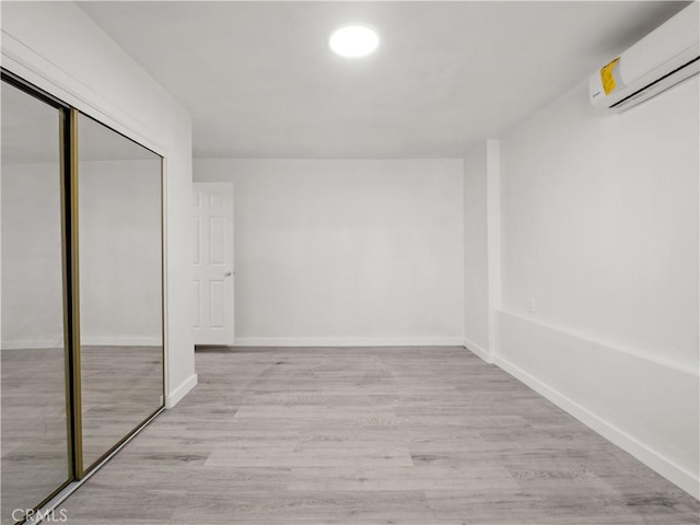 38809 Juniper Tree Rd, Palmdale, CA 93551 - unfurnished bedroom with an AC wall unit, light wood-type flooring, a closet, and baseboards
