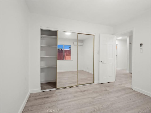 38809 Juniper Tree Rd, Palmdale, CA 93551 - unfurnished bedroom featuring a wall mounted air conditioner, wood finished floors, a closet, and baseboards