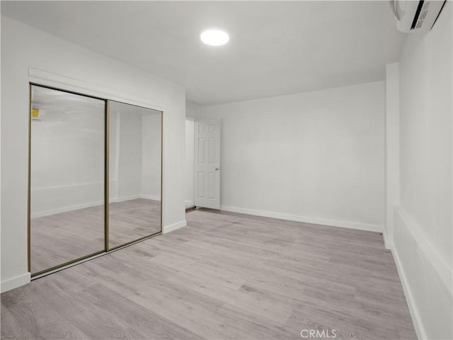 38809 Juniper Tree Rd, Palmdale, CA 93551 - unfurnished bedroom with an AC wall unit, wood finished floors, a closet, and baseboards