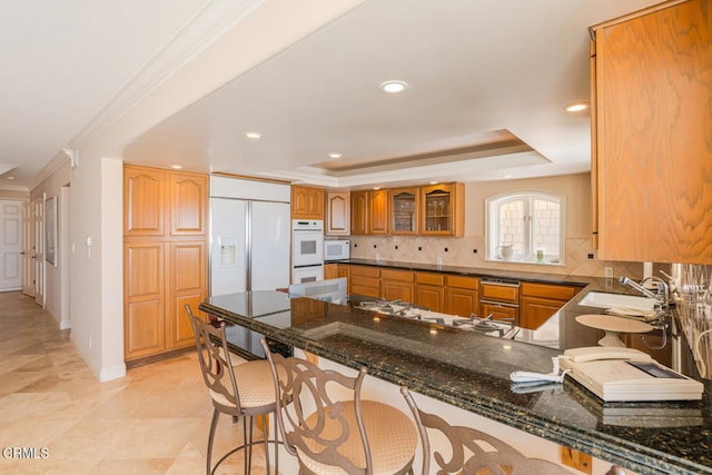 4165 Ocean Dr, Oxnard, CA 93035 - kitchen featuring a peninsula, a sink, white appliances, decorative backsplash, and brown cabinetry