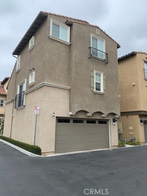 22111 Main St Unit 6, Carson, CA 90745 - rear view of property with a garage, stucco siding, driveway, and a tile roof
