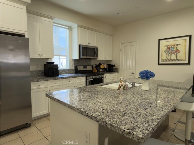 22111 Main St Unit 6, Carson, CA 90745 - kitchen with appliances with stainless steel finishes, light tile patterned flooring, a breakfast bar area, and white cabinets