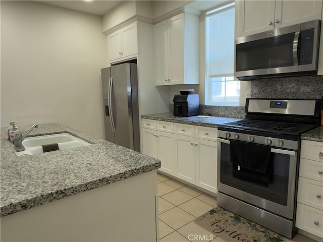 22111 Main St Unit 6, Carson, CA 90745 - kitchen with appliances with stainless steel finishes, white cabinetry, light stone countertops, and light tile patterned flooring