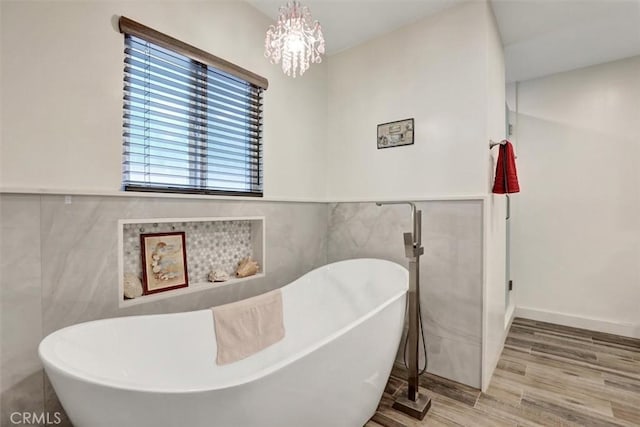12081 Martha Ann Dr, Los Alamitos, CA 90720 - bathroom with tile walls, wood finished floors, a freestanding bath, a chandelier, and a wainscoted wall