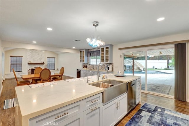 12081 Martha Ann Dr, Los Alamitos, CA 90720 - kitchen featuring a sink, stainless steel dishwasher, wood finished floors, glass insert cabinets, and plenty of natural light