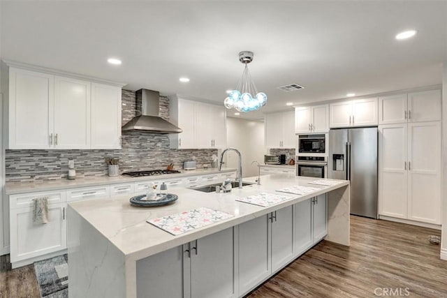 12081 Martha Ann Dr, Los Alamitos, CA 90720 - kitchen featuring appliances with stainless steel finishes, wall chimney exhaust hood, a sink, white cabinets, and recessed lighting