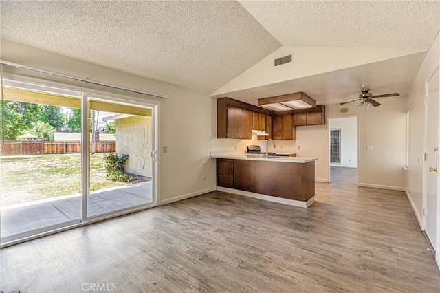 5712 Tupelo Dr, Sacramento, CA 95842 - kitchen with a peninsula, vaulted ceiling, wood finished floors, light countertops, and a textured ceiling