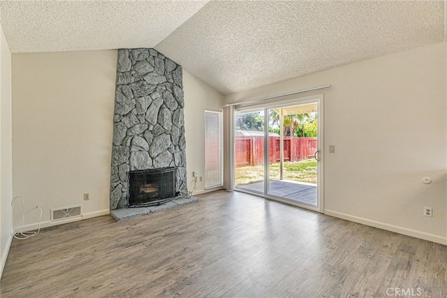 5712 Tupelo Dr, Sacramento, CA 95842 - unfurnished living room with wood finished floors, a textured ceiling, lofted ceiling, baseboards, and a stone fireplace