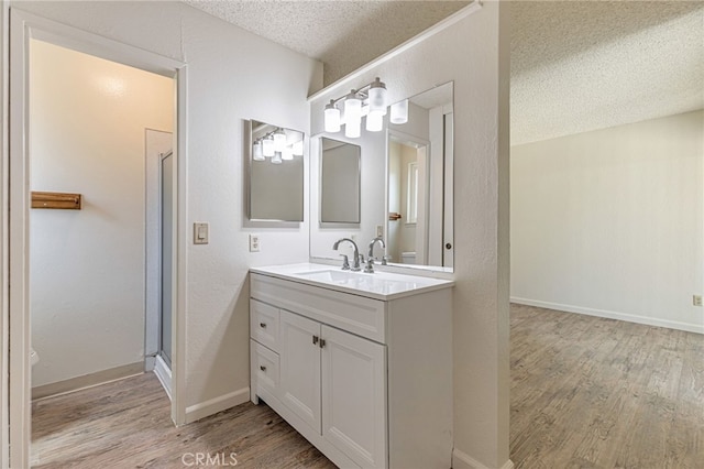 5712 Tupelo Dr, Sacramento, CA 95842 - bathroom with a textured ceiling, wood finished floors, vanity, toilet, and an enclosed shower