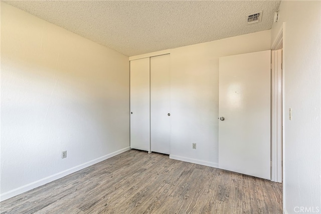 5712 Tupelo Dr, Sacramento, CA 95842 - unfurnished bedroom with wood finished floors, a textured ceiling, a closet, and baseboards