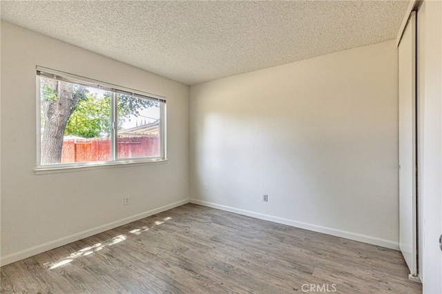 5712 Tupelo Dr, Sacramento, CA 95842 - empty room featuring wood finished floors, a textured ceiling, and baseboards