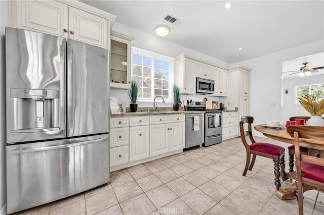 1107 Tennent Ave, Pinole, CA 94564 - kitchen featuring appliances with stainless steel finishes, a sink, light stone counters, light tile patterned floors, and a ceiling fan