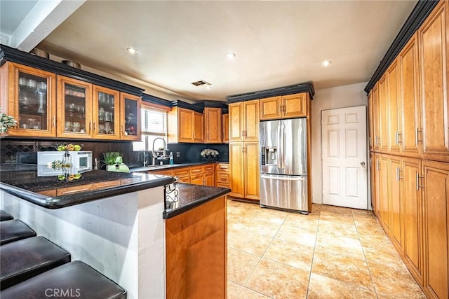 4639 Pine St, Pico Rivera, CA 90660 - kitchen featuring stainless steel refrigerator with ice dispenser, a peninsula, glass insert cabinets, a breakfast bar, and backsplash