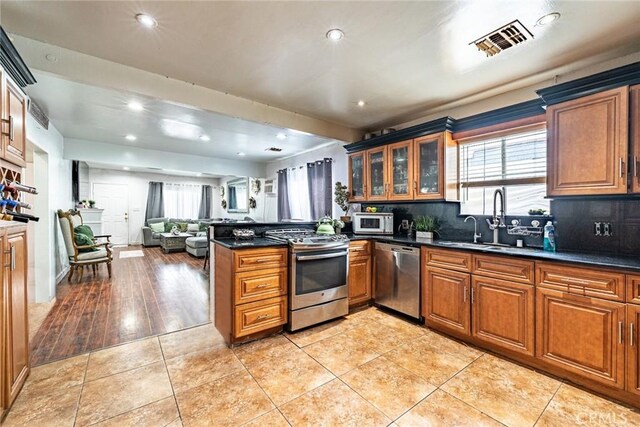 4639 Pine St, Pico Rivera, CA 90660 - kitchen with appliances with stainless steel finishes, brown cabinets, a peninsula, dark countertops, and recessed lighting