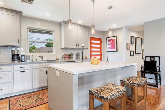 6320 E Los Santos Dr, Long Beach, CA 90815 - kitchen featuring tasteful backsplash, light countertops, light wood finished floors, a kitchen island, and a kitchen breakfast bar