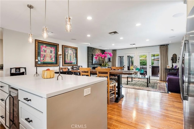 6320 E Los Santos Dr, Long Beach, CA 90815 - kitchen with open floor plan, beverage cooler, light countertops, hanging light fixtures, and light wood-type flooring