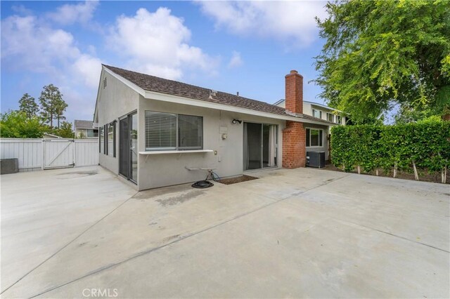 4252 Brookside St, Irvine, CA 92604 - rear view of house with a gate, central AC unit, a patio area, a chimney, and stucco siding