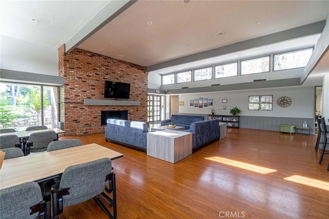 3605 W Hidden Ln Unit 112, Rolling Hills Estates, CA 90274 - living room featuring wood finished floors, a brick fireplace, a high ceiling, and a wainscoted wall
