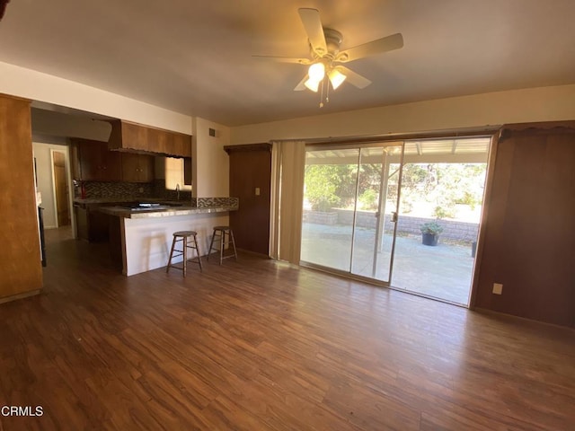 10315 Mcbroom St, Sunland, CA 91040 - kitchen featuring a ceiling fan, a peninsula, dark countertops, a kitchen bar, and dark wood-type flooring