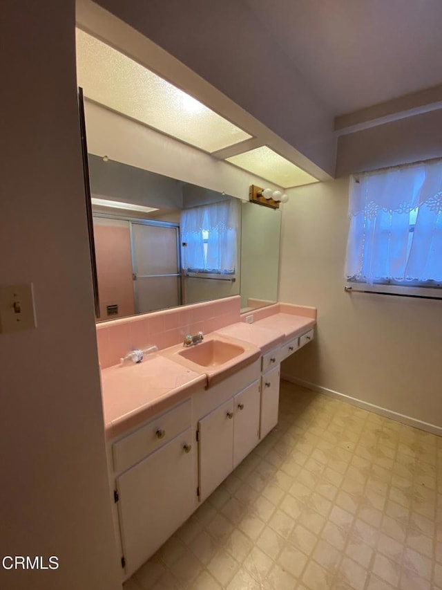 10315 Mcbroom St, Sunland, CA 91040 - bathroom with tile patterned floors, vanity, a shower with shower door, tasteful backsplash, and baseboards