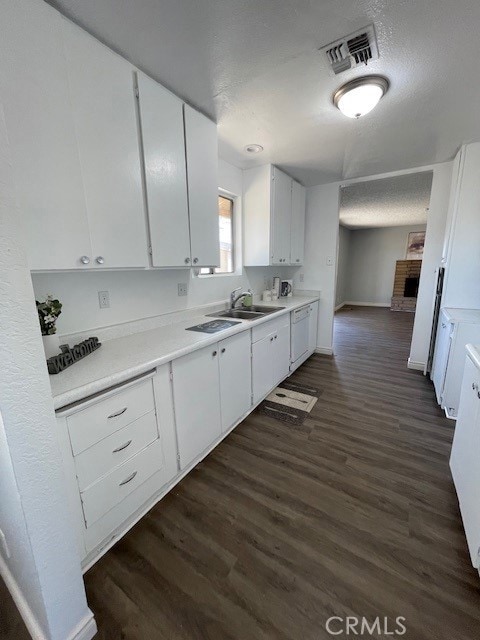 15577 Nisqualli Rd, Victorville, CA 92395 - kitchen with a fireplace, white cabinets, light countertops, and dark wood-style floors