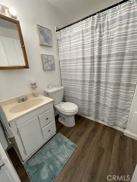 15577 Nisqualli Rd, Victorville, CA 92395 - full bathroom featuring vanity, wood finished floors, and curtained shower