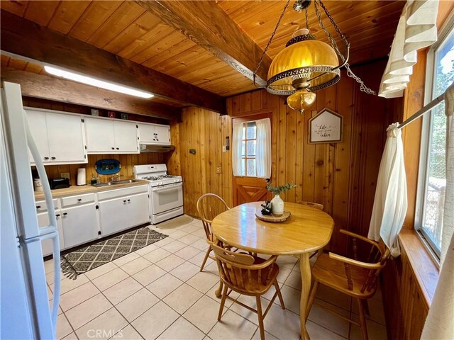 2076 8th Ln, Big Bear City, CA 92314 - dining space featuring wood ceiling with exposed beams, light tile patterned flooring, wood walls, and healthy amount of natural light