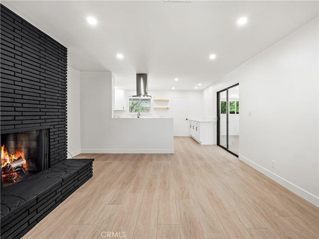 38537 Desert View Dr, Palmdale, CA 93551 - unfurnished living room with light wood-style floors, a fireplace, baseboards, recessed lighting, and a sink