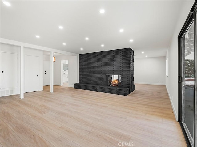 38537 Desert View Dr, Palmdale, CA 93551 - unfurnished living room with light wood-style flooring, a multi sided fireplace, baseboards, recessed lighting, and a sink