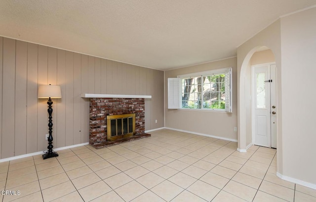 29421 Florabunda Rd, Canyon Country, CA 91387 - unfurnished living room with arched walkways, a brick fireplace, light tile patterned flooring, baseboards, and a textured ceiling