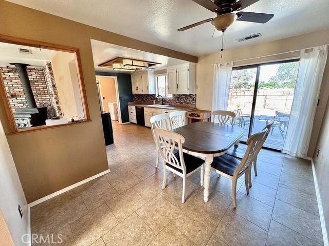 3646 Kirkwood Rd, Corning, CA 96021 - dining area featuring a wood stove, a ceiling fan, a tray ceiling, and a textured ceiling