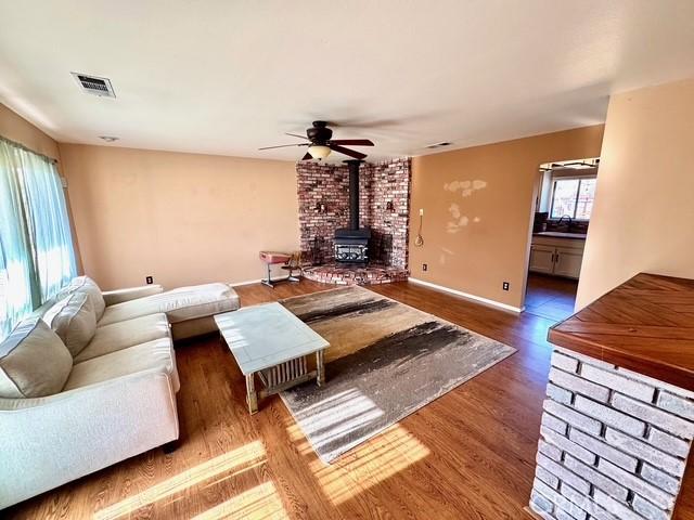 3646 Kirkwood Rd, Corning, CA 96021 - living area with a wood stove, a ceiling fan, and wood finished floors
