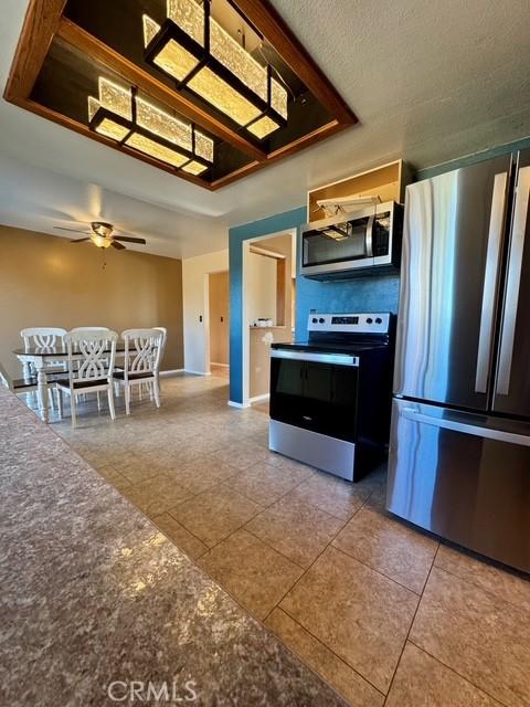 3646 Kirkwood Rd, Corning, CA 96021 - kitchen featuring appliances with stainless steel finishes, tile patterned floors, a ceiling fan, and dark countertops