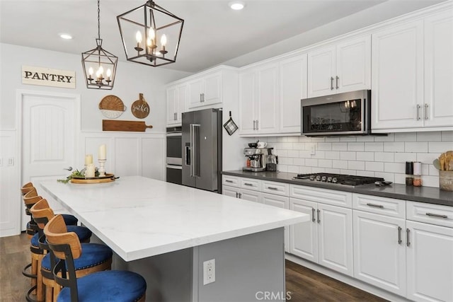 32954 Marin Fields Rd, Winchester, CA 92596 - kitchen with stainless steel appliances, white cabinetry, a center island, dark wood finished floors, and wainscoting