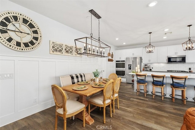 32954 Marin Fields Rd, Winchester, CA 92596 - dining area featuring a chandelier, a decorative wall, dark wood finished floors, recessed lighting, and a wainscoted wall