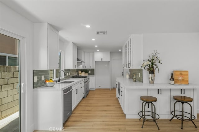 16791 Glenhaven Ln, Huntington Beach, CA 92647 - kitchen featuring stainless steel appliances, a sink, glass insert cabinets, a kitchen breakfast bar, and backsplash