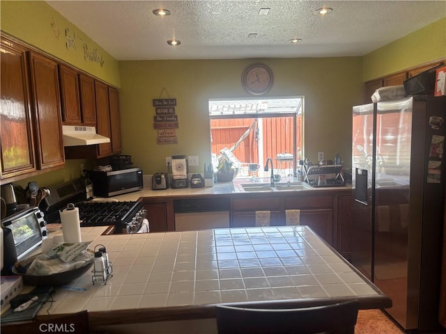 116 Evergreen Pl, Perris, CA 92571 - kitchen with tile counters, appliances with stainless steel finishes, under cabinet range hood, a sink, and a textured ceiling