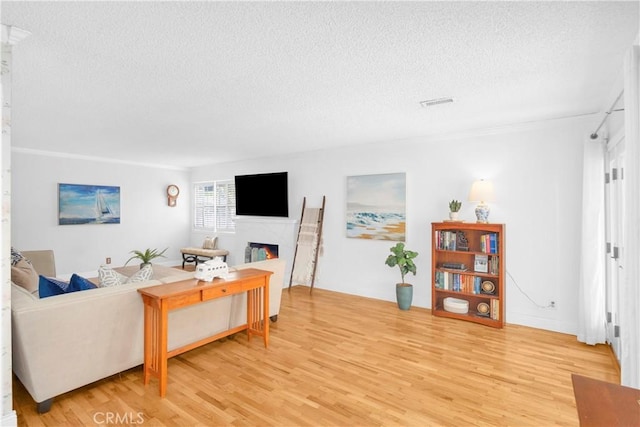 8381 E Hendrie St, Long Beach, CA 90808 - living area with a textured ceiling, light wood finished floors, a warm lit fireplace, and crown molding