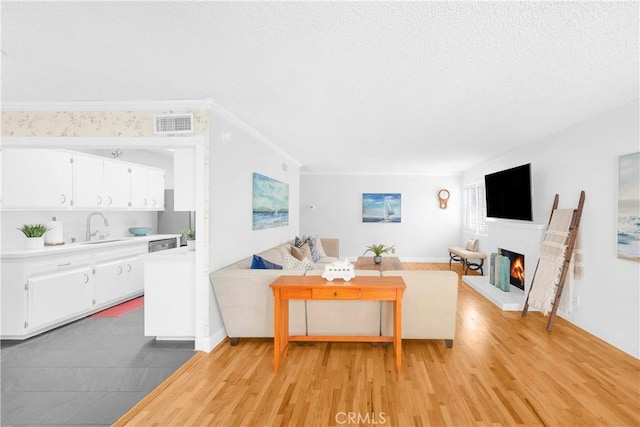 8381 E Hendrie St, Long Beach, CA 90808 - living room with a warm lit fireplace, light wood-style flooring, and a textured ceiling