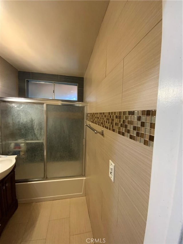 12536 Fineview St, El Monte, CA 91732 - full bathroom featuring vanity, tile walls, and bath / shower combo with glass door