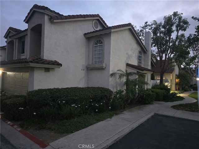 29 Carnation Unit 64, Rancho Santa Margarita, CA 92688 - view of home's exterior with stucco siding, a tiled roof, and an attached garage