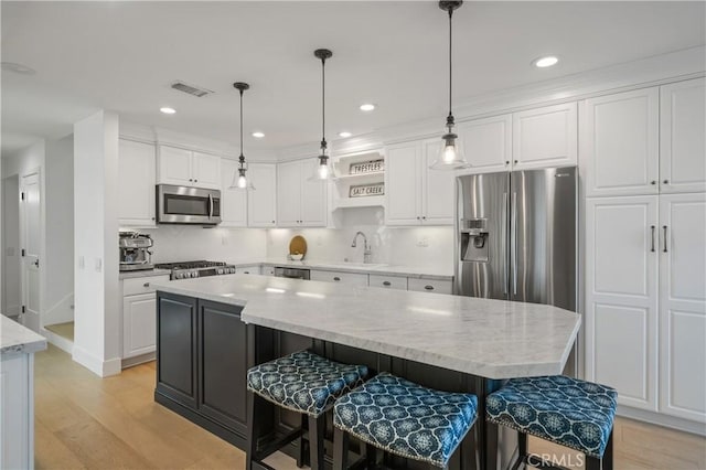 28332 Via Alfonse, Laguna Niguel, CA 92677 - kitchen featuring appliances with stainless steel finishes, light wood-style flooring, a sink, white cabinets, and a breakfast bar area