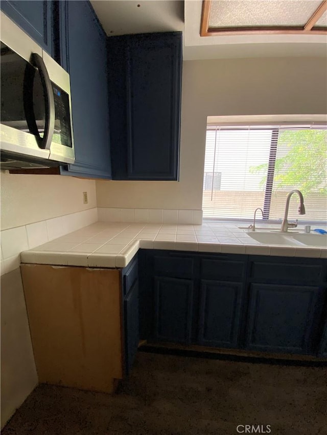 43321 Cottage Ln, Lancaster, CA 93536 - kitchen featuring stainless steel microwave, a sink, blue cabinetry, and tile countertops